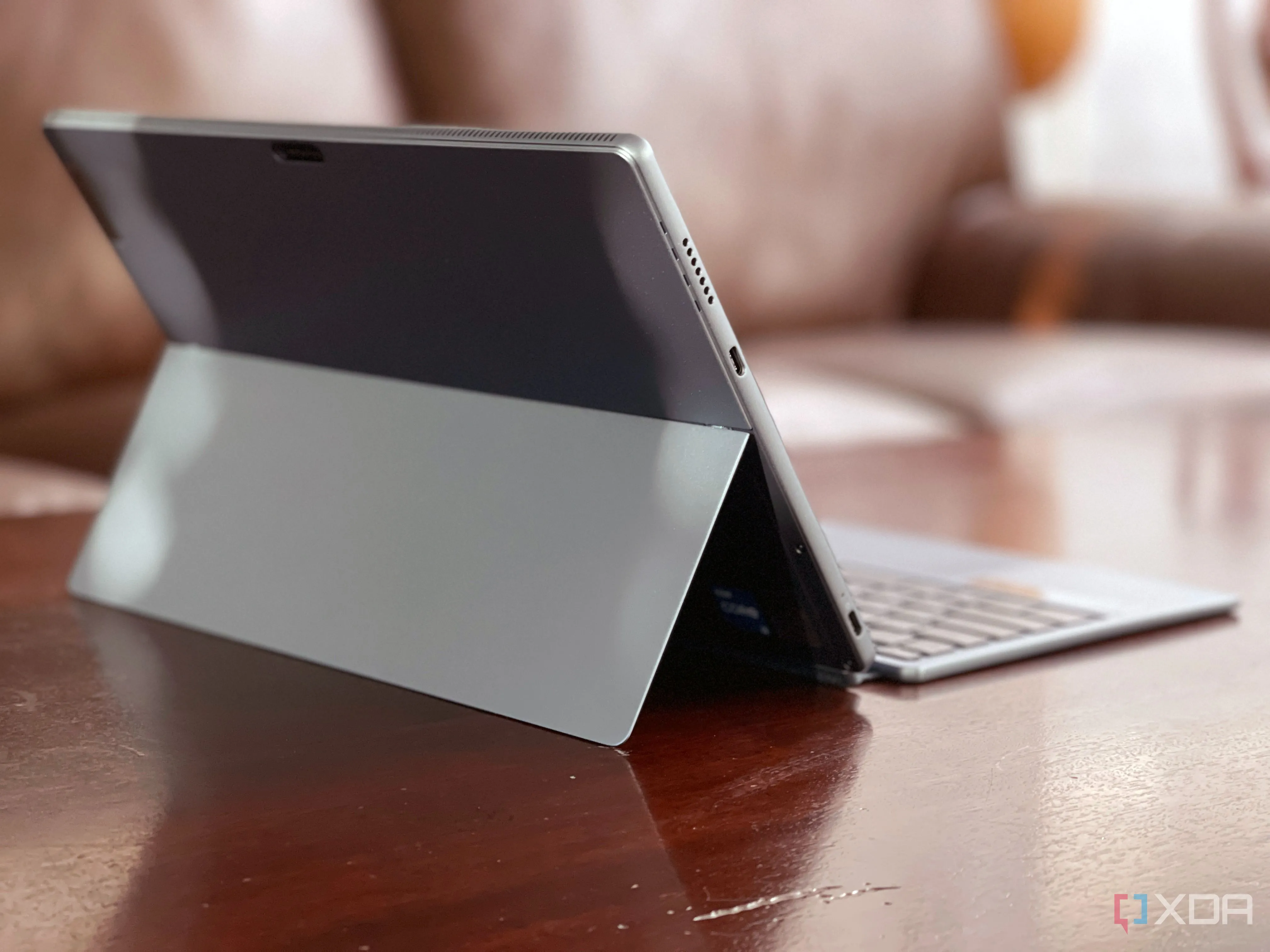 IdeaPad Duet 5i nhìn từ phía sau, đặt trên bàn với ghế sofa ở phía sau