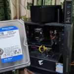 Người cầm ổ cứng HDD trước máy tính PC và hai thiết bị NAS TerraMaster, minh họa cho giải pháp mở rộng bộ nhớ bằng NAS