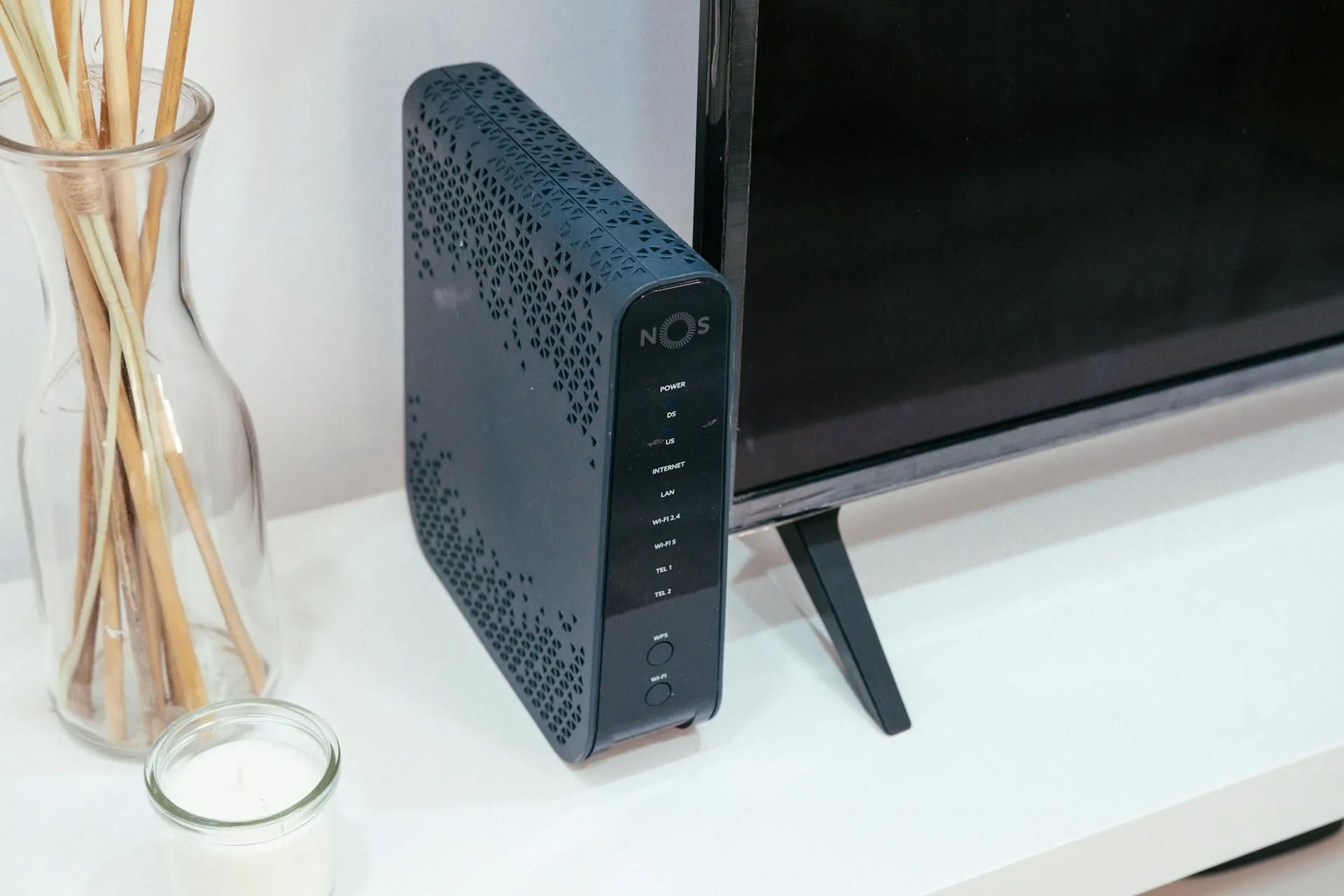 Router mạng đặt cạnh ti vi và lư hương, biểu thị kết nối internet trong môi trường gia đình